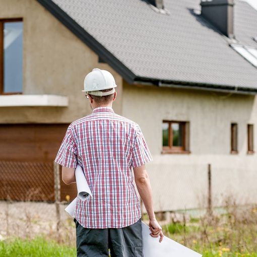 Construction expert evaluating a new residential house in Ireland, with blueprint in hand for dream home building project.