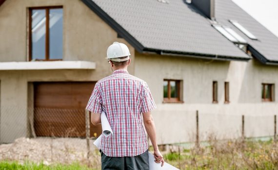 Construction expert evaluating a new residential house in Ireland, with blueprint in hand for dream home building project.